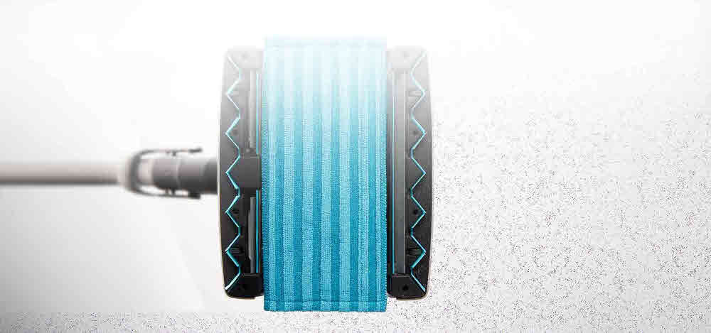 Obraz przedstawia głowicę mopującą odkurzacza z niebieską, prążkowaną nakładką. W tle widoczna jest powierzchnia z drobnymi cząstkami kurzu.