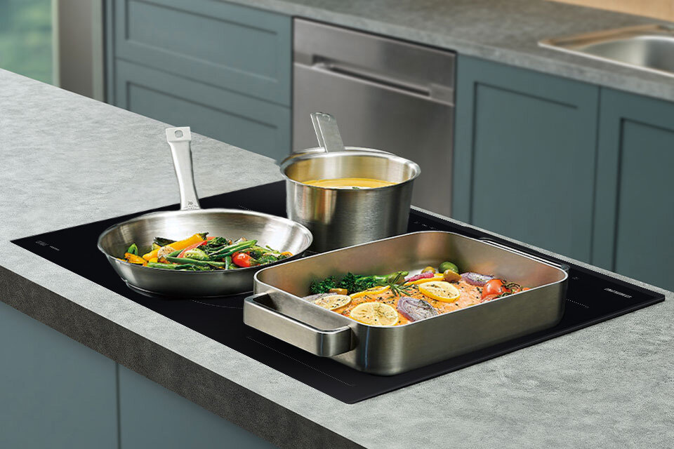 Na kuchennej płycie indukcyjnej marki Samsung NZ84C5047GK/U2 ustawione są metalowe garnki