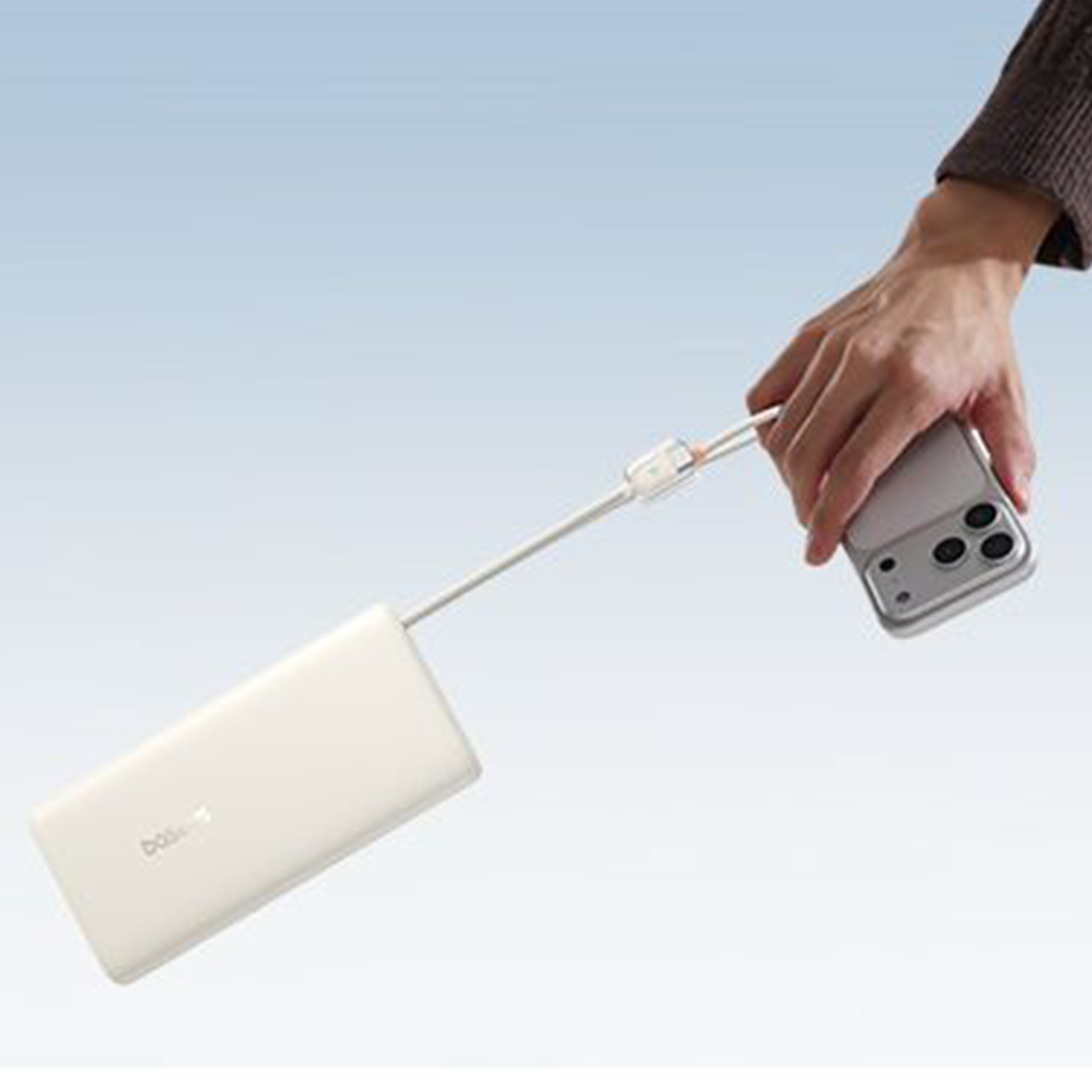 Osoba trzyma smartfon podłączony do białego powerbanku za pomocą kabla. Na powerbanku widoczne jest logo \'Baseus\'.