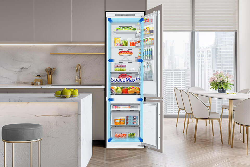 Otwarta lodówka w nowoczesnej kuchni, wypełniona różnorodnymi produktami spożywczymi. Na drzwiach lodówki widoczny jest napis \'SpaceMax™\'.