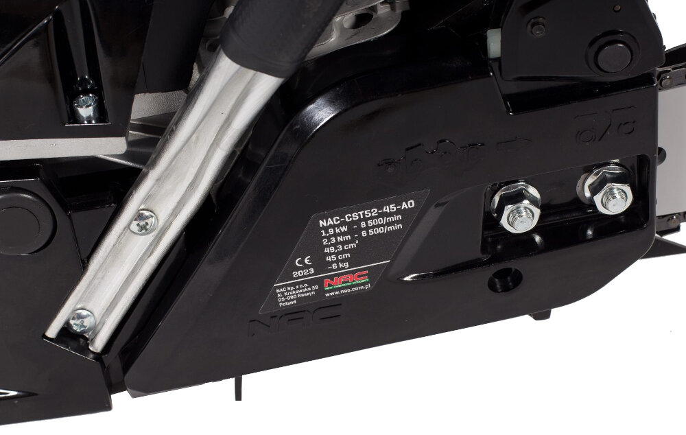 Zbliżenie na część piły spalinowej z widoczną tabliczką znamionową. Na tabliczce znajduje się tekst: \'NAC-CST52-45-AO 3.0 kW 2.3 cm³ 49.3 cm 2023 NAC\'.