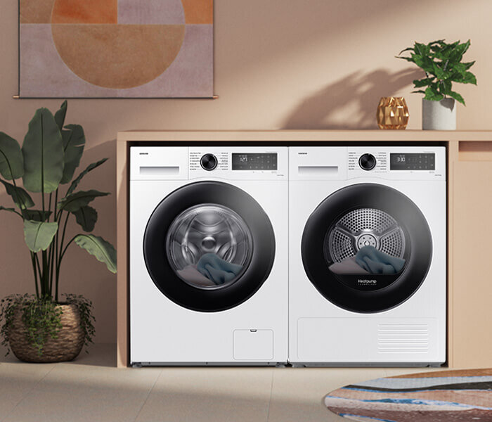 Na obrazie widoczne są dwie białe pralki z czarnymi drzwiczkami, ustawione obok siebie w zabudowie. Na panelach sterowania widoczne są pokrętła i wyświetlacze cyfrowe.