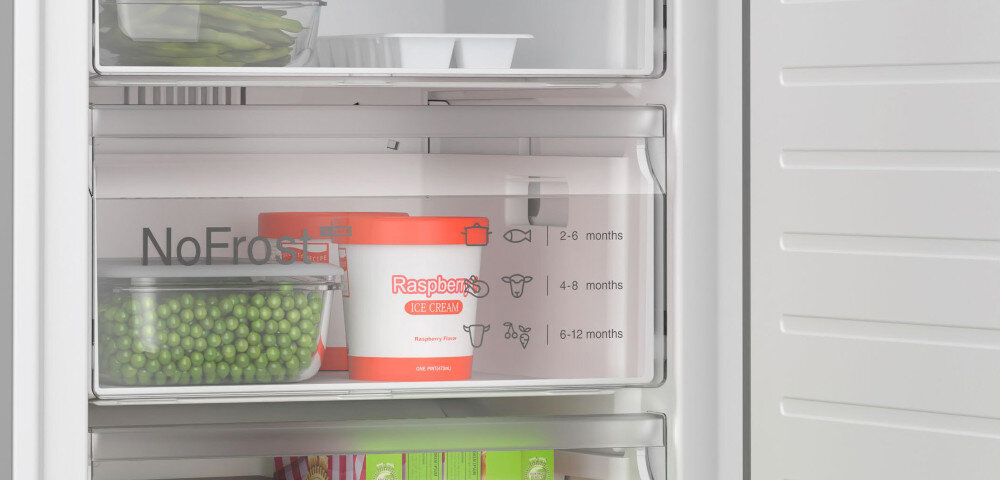 Wnętrze zamrażarki z widocznymi pojemnikami na żywność, w tym opakowanie lodów z napisem \'Raspberry Ice Cream\'. Na szufladzie widoczny jest napis \'NoFrost\' oraz symbole z oznaczeniami czasowymi przechowywania żywności.
