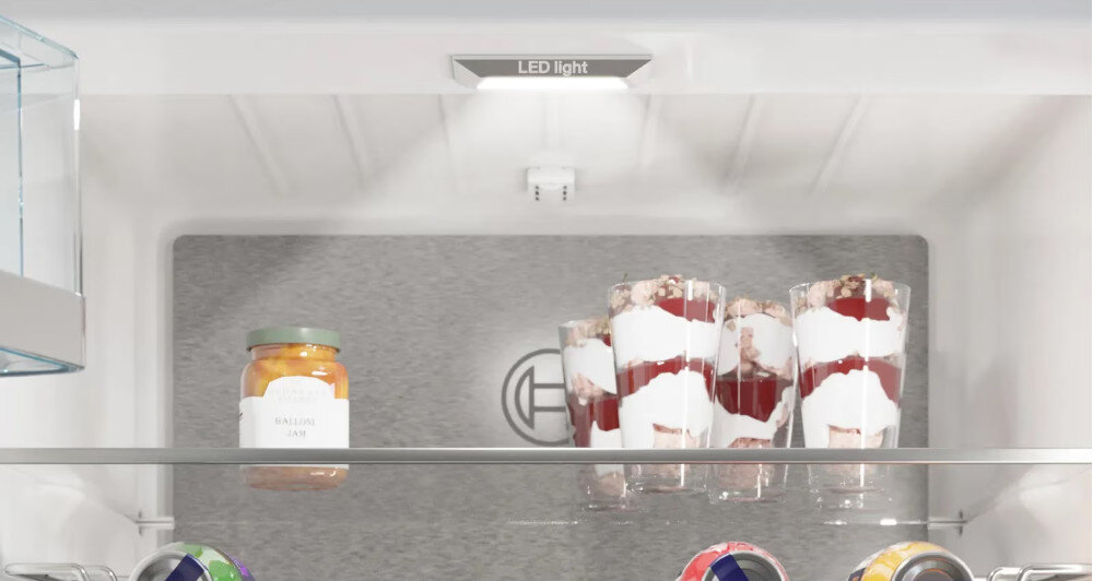 Wnętrze lodówki z półką, na której znajdują się słoik z przetworami i trzy szklanki z deserem. Na górze widoczny napis \'LED light\'.