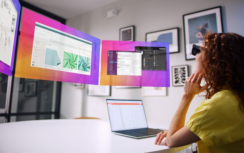 Okulary VITURE XR Luma Ultra Czarny Kobieta siedzi przy biurku z laptopem i nałożonym okularami VR, które wyświetlają obraz na 3 ekranach korekcja dioptrii do -4.0D regulacja IPD zakres elektrochromatyczne soczewki przyciemnianie obrazu immersja