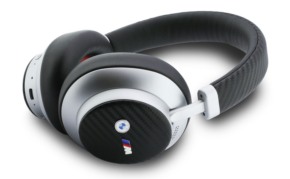 Srebrne słuchawki nauszne z czarnymi elementami i logo BMW M na nauszniku. Pałąk pokryty jest materiałem o wyglądzie włókna węglowego.