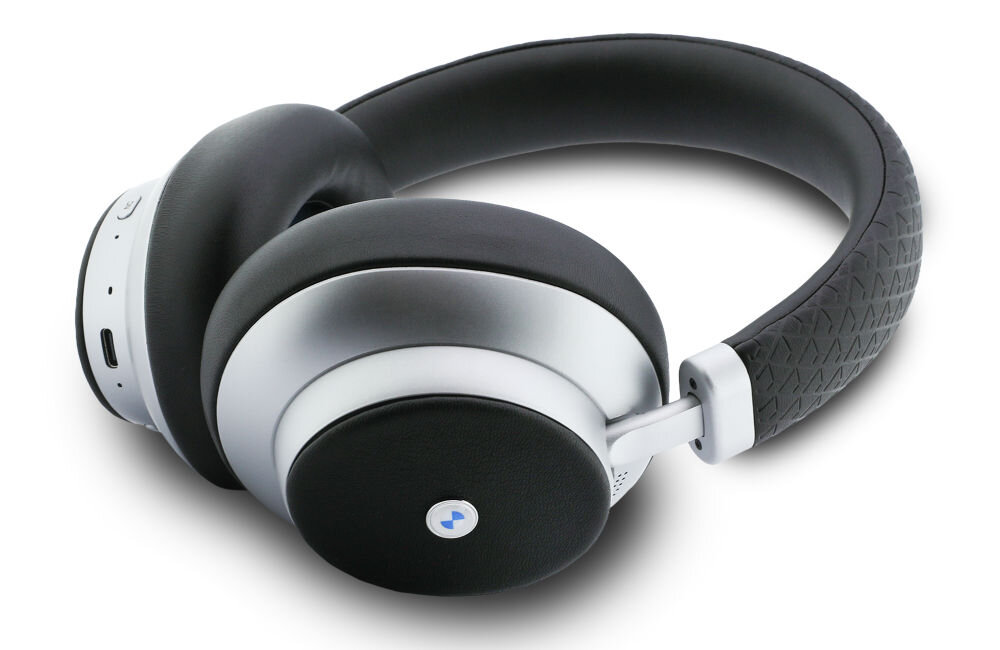 Srebrne słuchawki nauszne z czarnymi poduszkami i pałąkiem, na jednej z muszli widoczne jest logo w kształcie okręgu z niebieskim elementem. Na obudowie znajduje się port USB-C oraz przyciski sterujące.