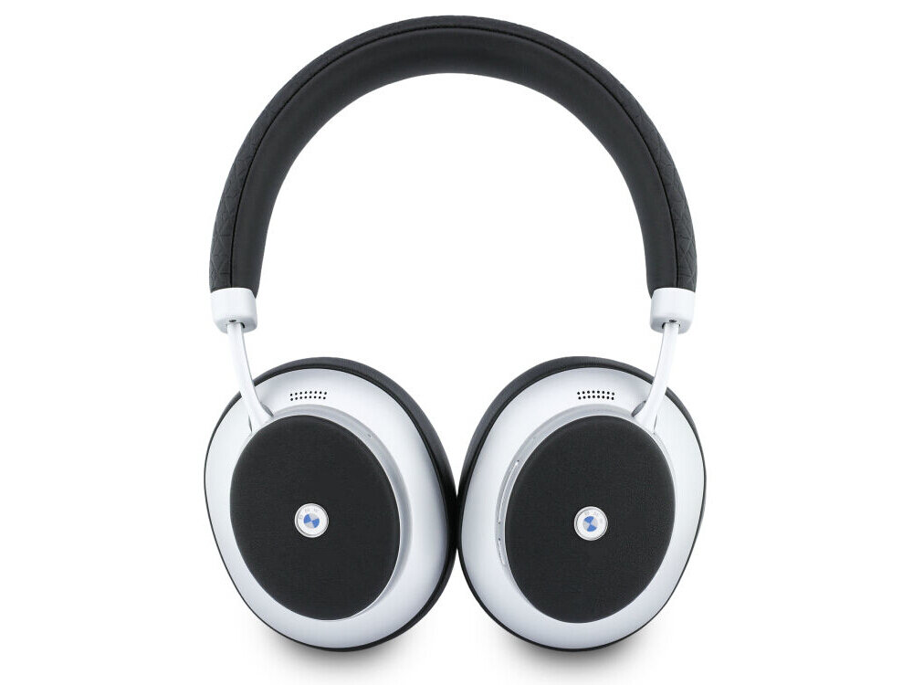 Srebrne słuchawki nauszne z czarnymi poduszkami i metalowym logo na środku każdej muszli. Pałąk jest wyściełany czarnym materiałem.