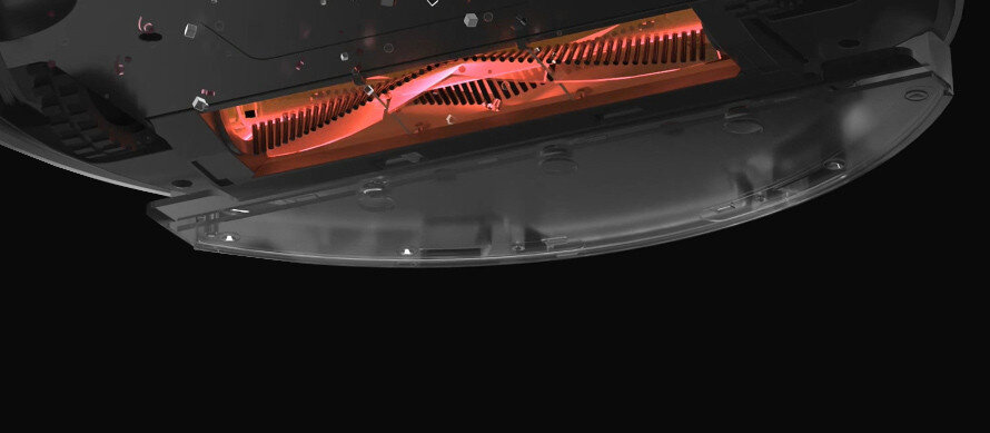 Zdjęcie przedstawia dolną część robota sprzątającego z widoczną szczotką w kolorze pomarańczowym. Tło jest czarne, a elementy konstrukcji są ciemne.