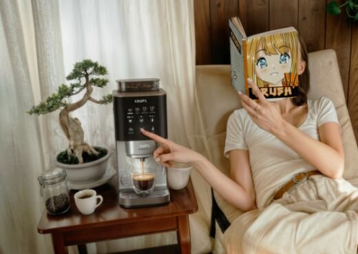 Kobieta leży na fotelu z książką, obok Ekspres do kawy KRUPS Coffee Crush na stoliczku.