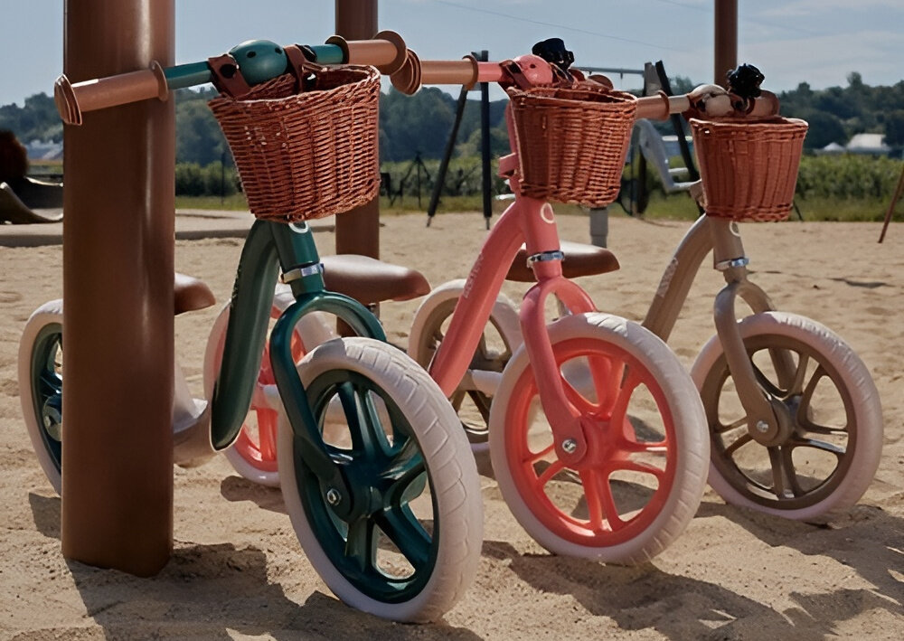 Rowerek biegowy LIONELO Alex Plus Zielony trzy rowerki w różnych kolorach ustawione obok siebie w tle piasek radość zabawa nauka jazdy nauka równowagi rozwój motoryczny