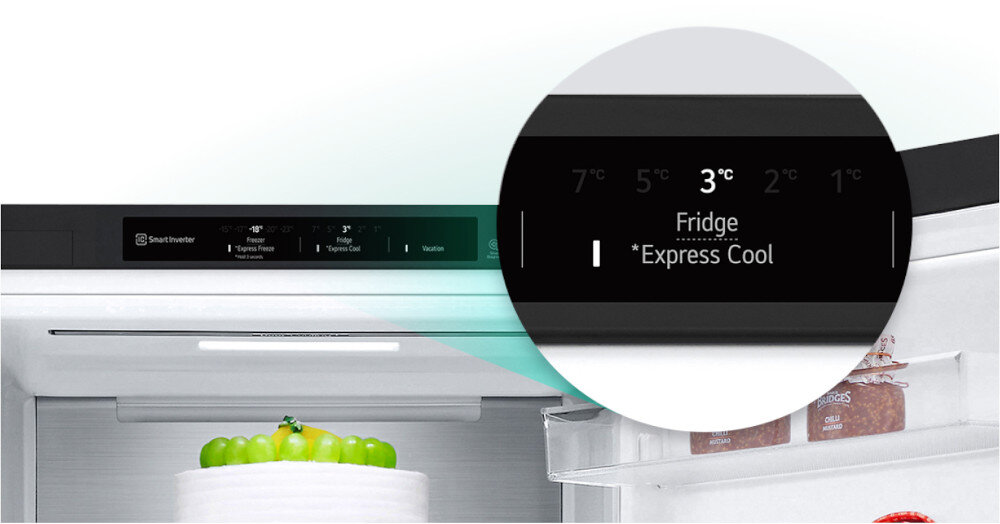 Obraz przedstawia wnętrze lodówki z wyświetlaczem pokazującym temperaturę 3°C oraz funkcję \'Fridge *Express Cool\'. Na półce znajduje się tort ozdobiony zielonymi owocami.