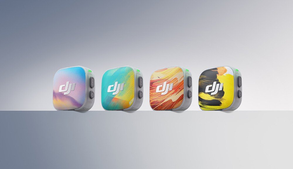 System bezprzewodowy DJI Mic Mini 2 Cztery kwadratowe nadajniki mikrofonowe ustawione w rzędzie na gładkiej powierzchni. Każdy z nich ma na froncie inną, barwną grafikę przypominającą plamy farby lub abstrakcyjne pejzaże, a po bokach widoczne są przyciski funkcyjne i diody kontrolne, magnetyczne osłony, kolory
