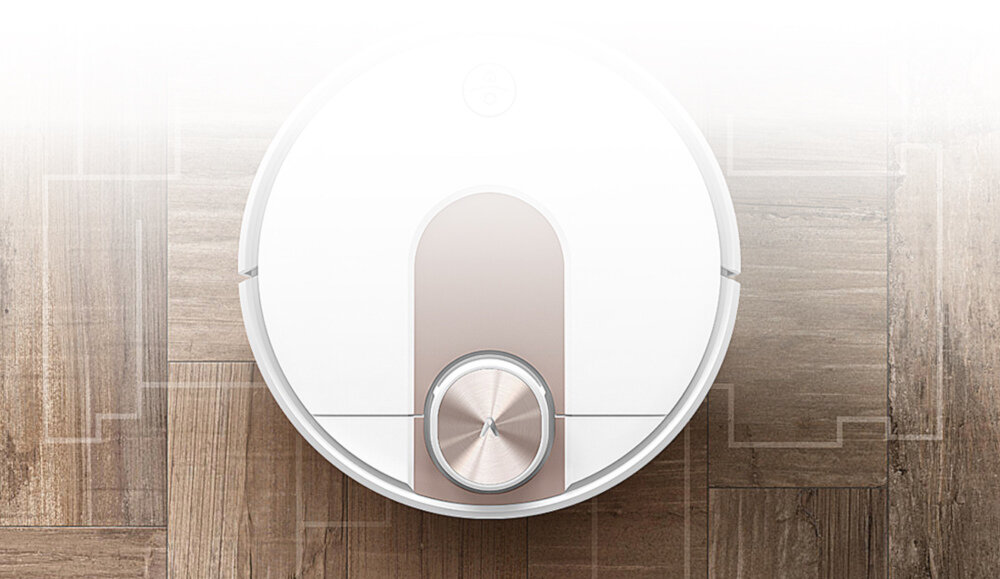 Na drewnianej podłodze znajduje się okrągły, biały robot sprzątający z metalicznym elementem na środku. W tle widoczne są delikatne linie przypominające plan pomieszczenia.