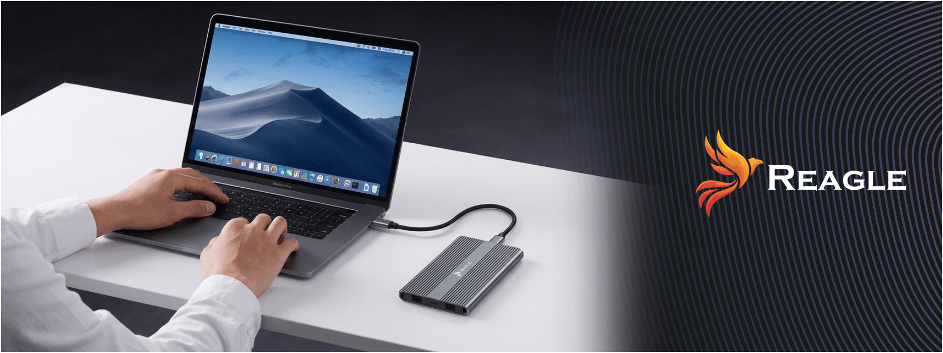 Osoba korzysta z laptopa, do którego podłączona jest dwuzatokowa obudowa REAGLE NVMe przez kabel USB-C. Po prawej stronie widoczne jest logo REAGLE na ciemnym tle.