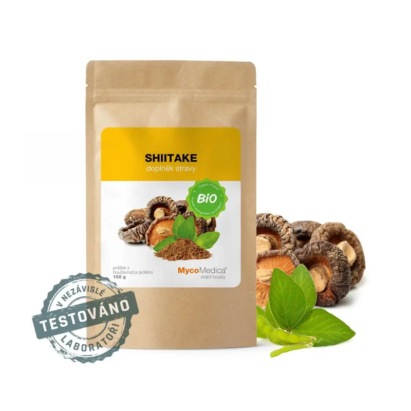 Opakowanie z napisem \'SHIITAKE doplněk stravy\' oraz logo \'MycoMedica\'. Obok opakowania widoczne są grzyby shiitake i zielone liście.