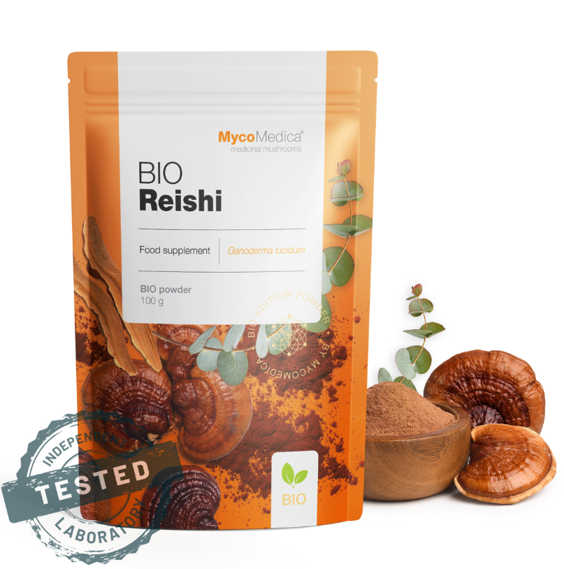 Opakowanie produktu MycoMedica Bio Reishi w proszku 100g z widocznym napisem \'Food supplement Ganoderma lucidum\'. Obok opakowania znajdują się grzyby i miseczka z proszkiem.