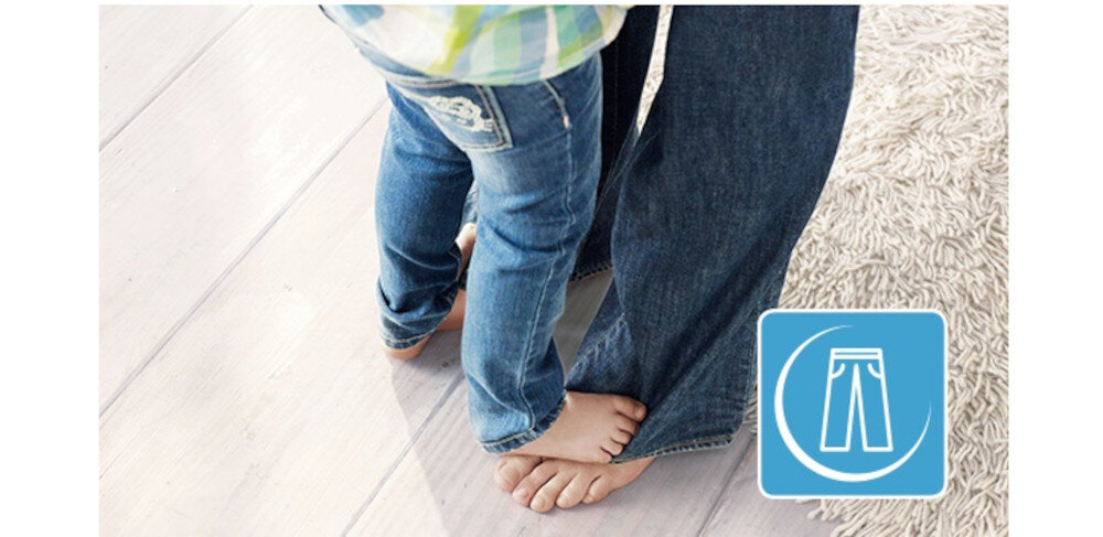 Dwie osoby stoją boso na podłodze, jedna z nich ma na sobie dżinsy. Obok znajduje się niebieska ikona z symbolem spodni.