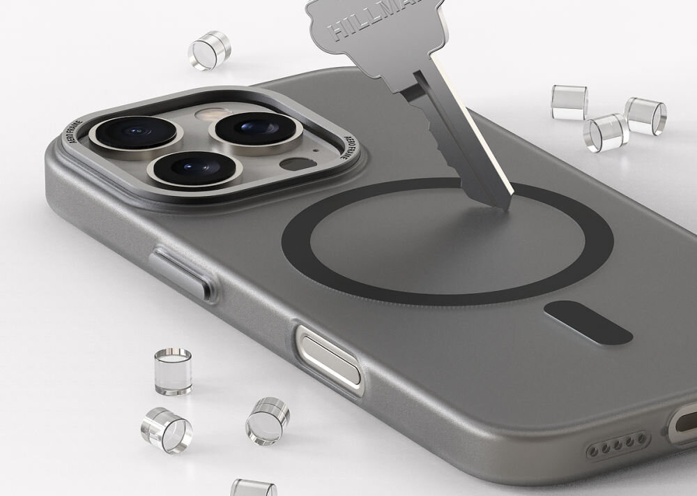 Na obrazie widoczne jest etui na telefon z trzema obiektywami aparatu, na które skierowany jest klucz. W tle znajdują się małe, metalowe elementy cylindryczne.