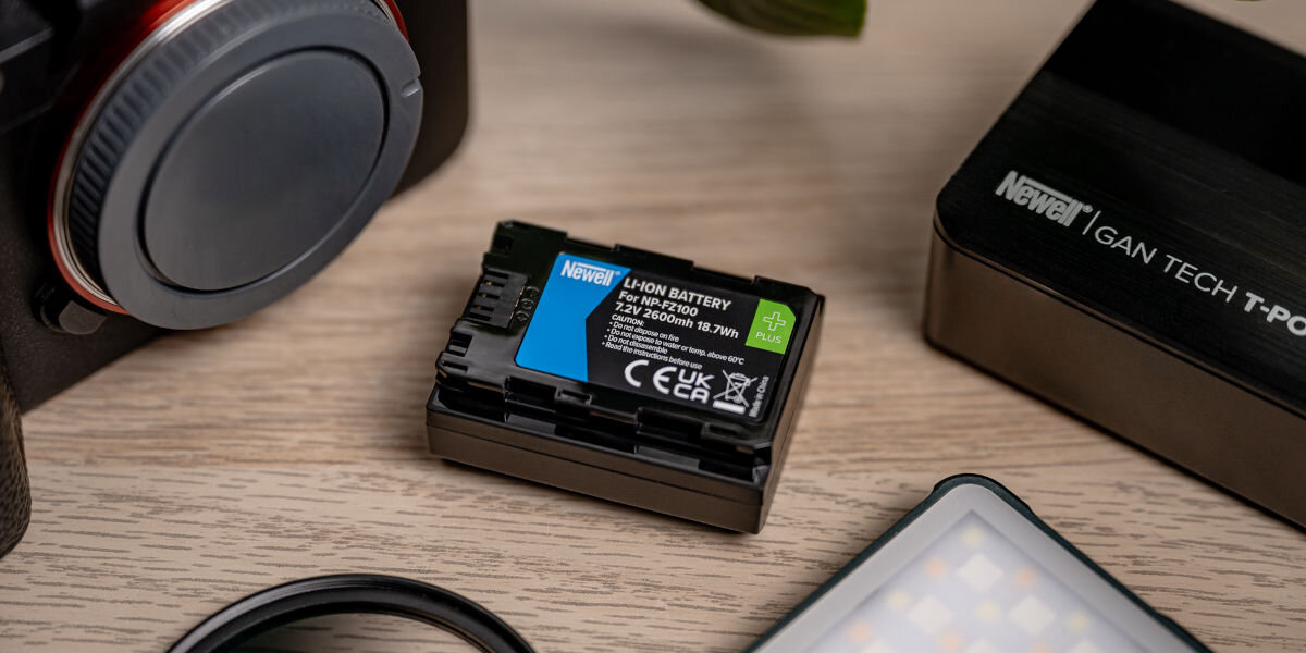 Akumulator NEWELL 2280 mAh do Sony NP-FZ100 Plus, ładowanie, zamiennik, zastępowanie, zamiana, akumulator leży na blacie wśród elektroniki